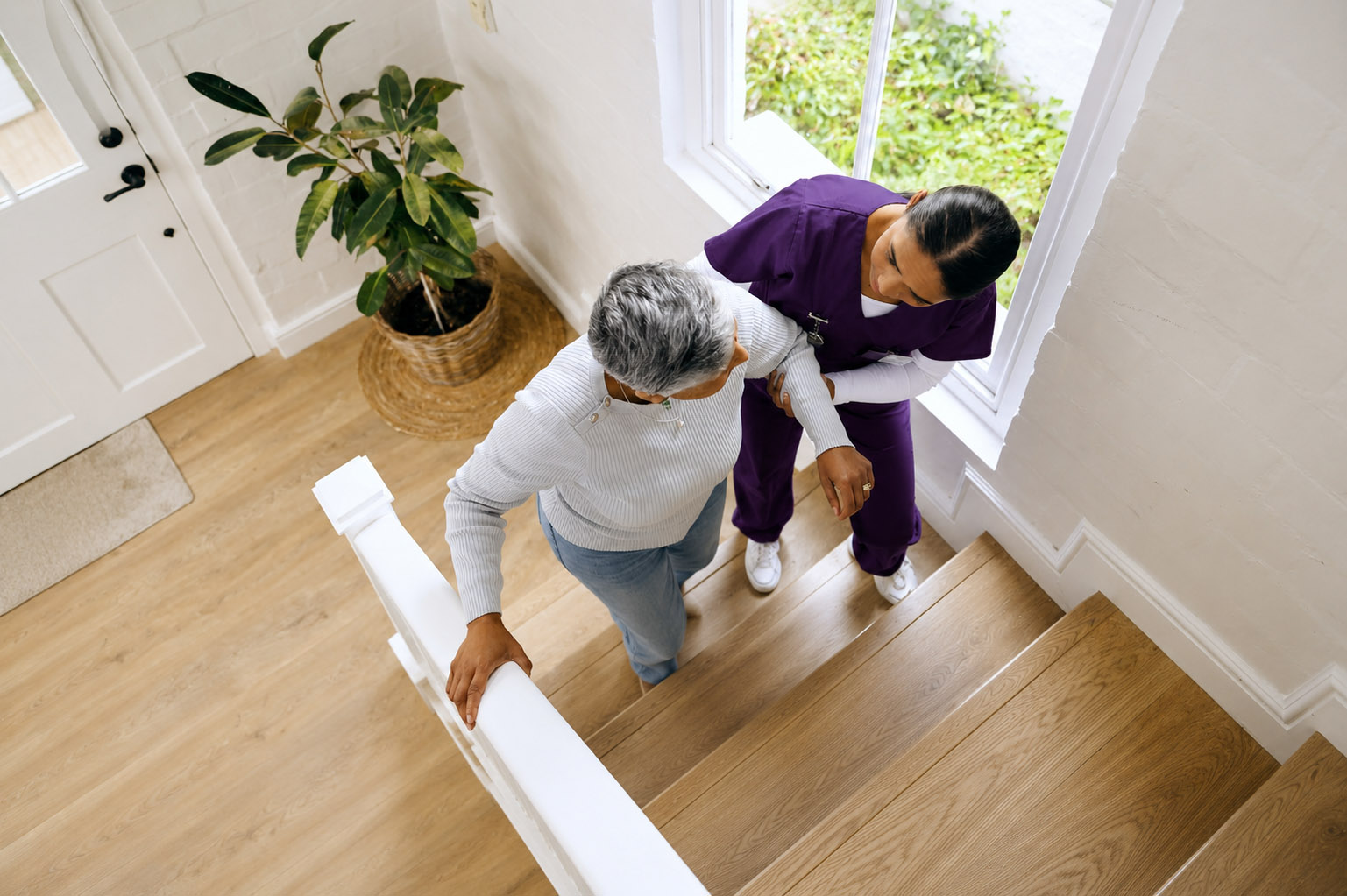 Noble Care carer assisting elderly client on the stairs at home
